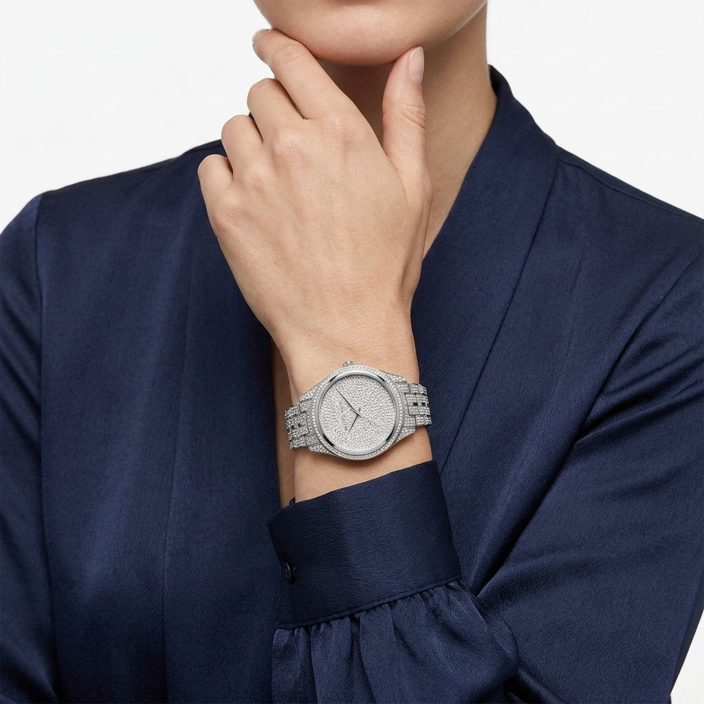 A close-up of a woman wearing a silver-toned diamond-encrusted watch with a matching bracelet, paired with a dark navy satin blouse against a clean white background.