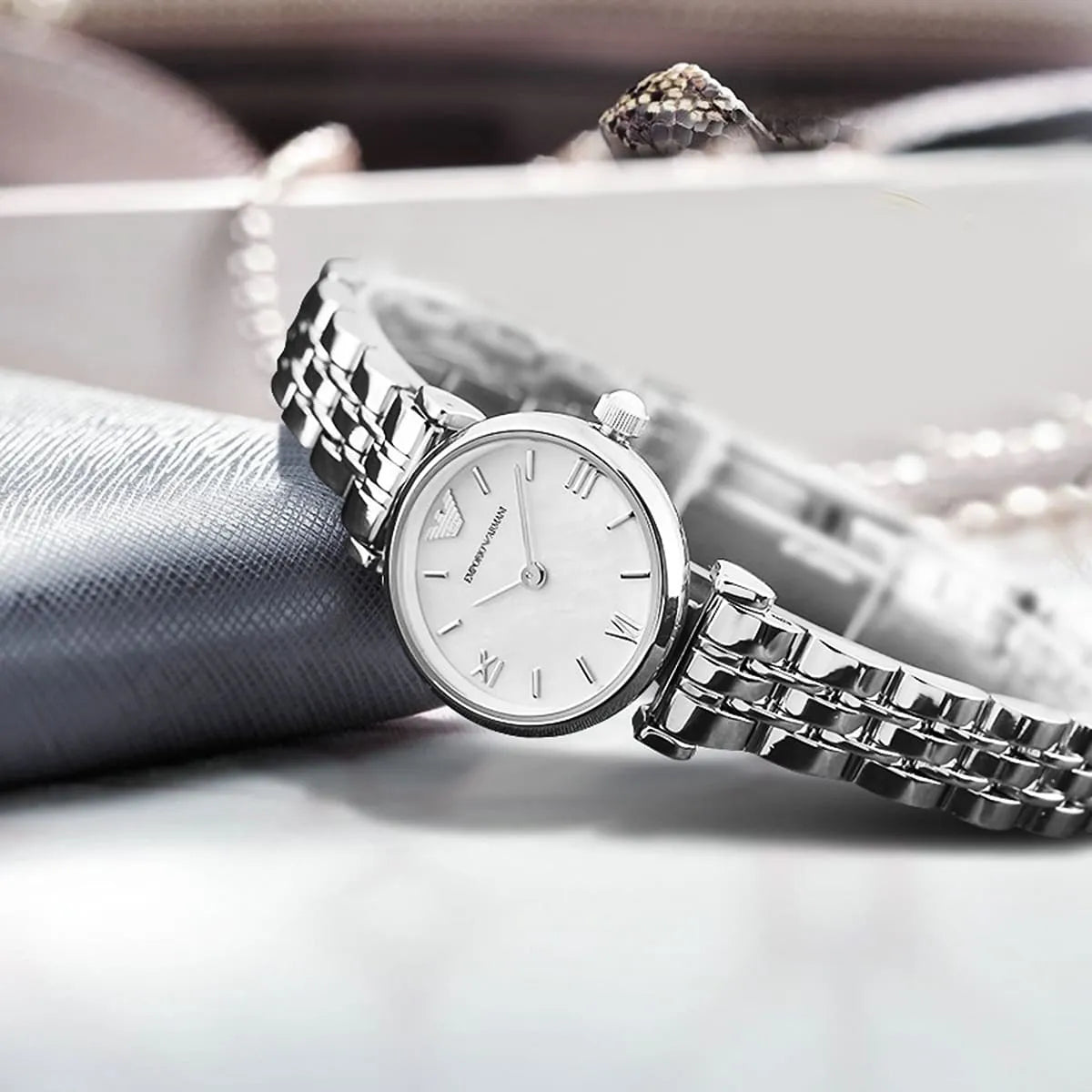 Emporio Armani AR1763 watch styled on gray fabric with jewelry, white dial and silver bracelet